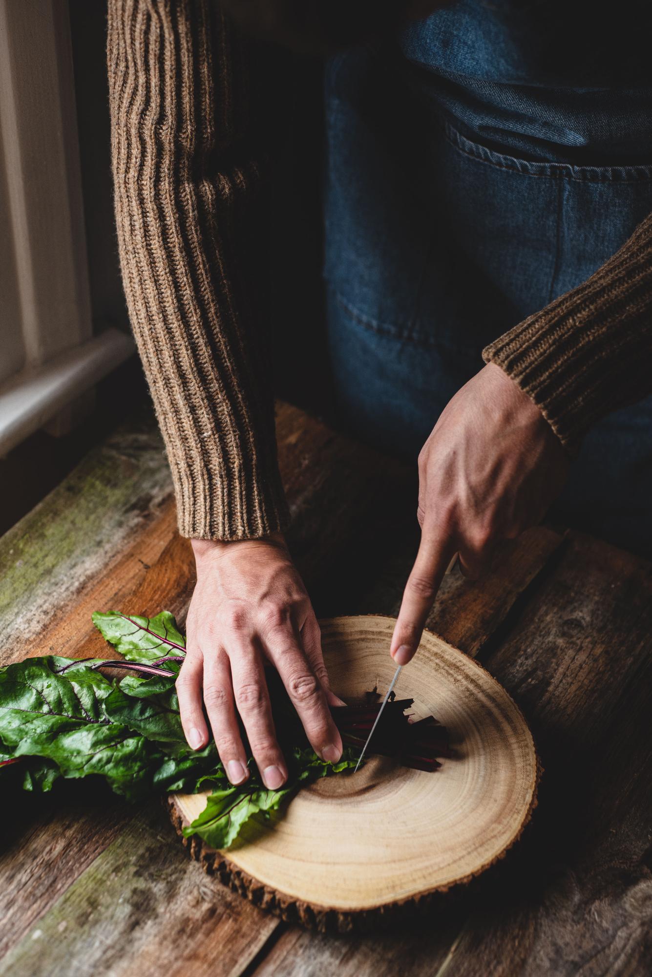 Hands preparing herbs on wooden board